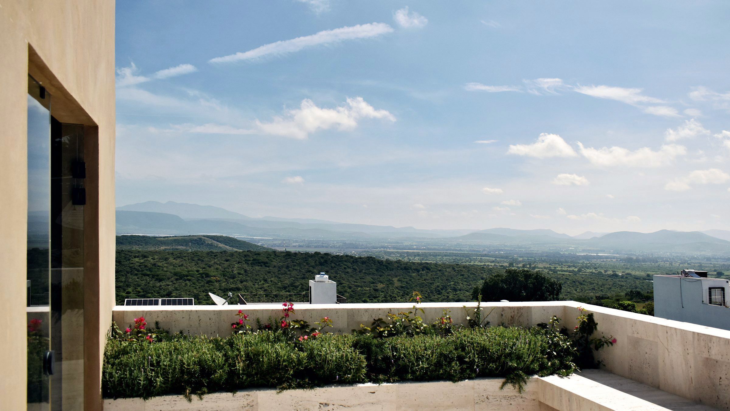Terraza de travertino de Casa Ceiba 92 con jardinera y vista al valle y la sierra